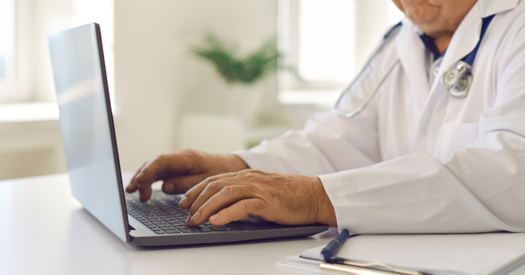 electronic health records ehr definition shown by senior doc working on laptop in hospital